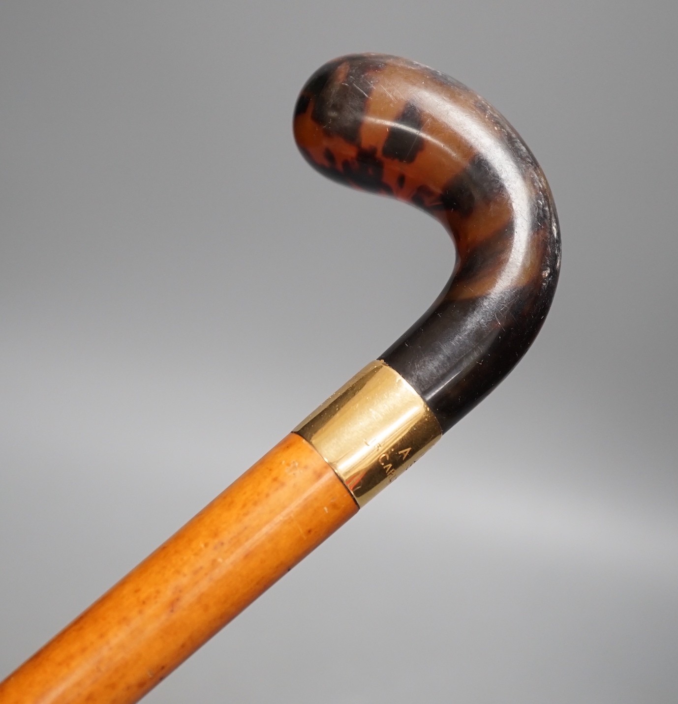 An 18ct gold collared malacca cane, with a horn handled handle, stained as tortoiseshell, 94 cms long